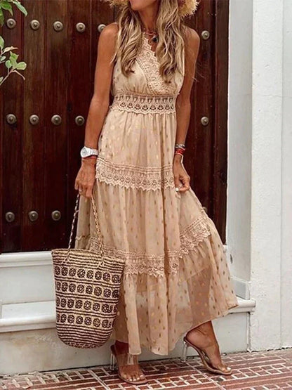 Frau in langem, ärmellosem, beigem Sommerkleid mit Spitzenmuster, hält geflochtene Strohtasche, steht vor Holztür. Sommermode, Boho-Stil.