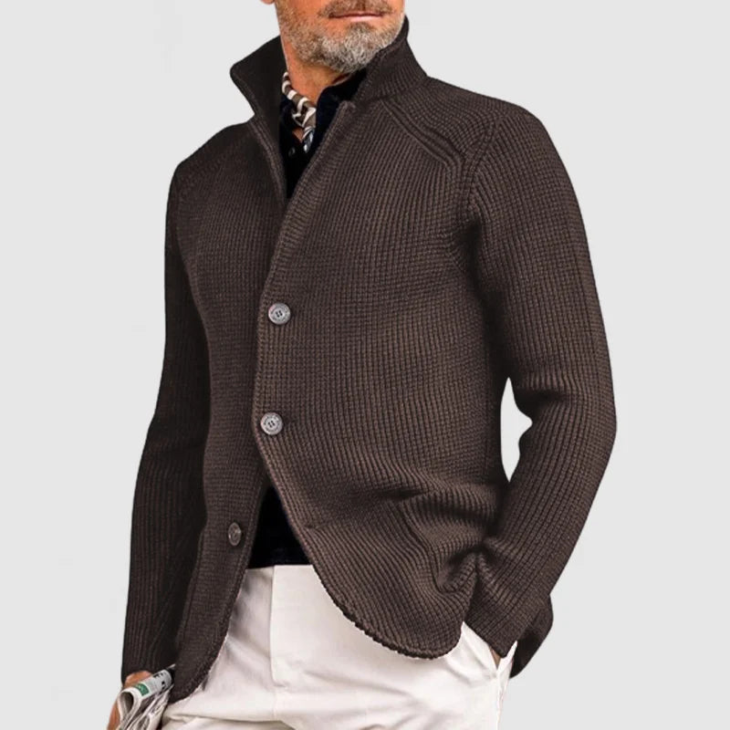 Mann in braunem Strickblazer mit Stehkragen, weißer Hose und Schal. Elegante Herrenmode, stilvoller Look, modischer Blazer für Herbst/Winter.
