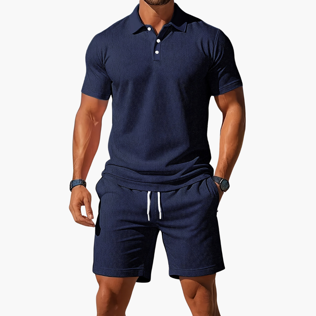 Mann in dunkelblauem Poloshirt und Shorts, sportlich-eleganter Look, Sommermode für Herren, Freizeitkleidung, stilvoll und modern.