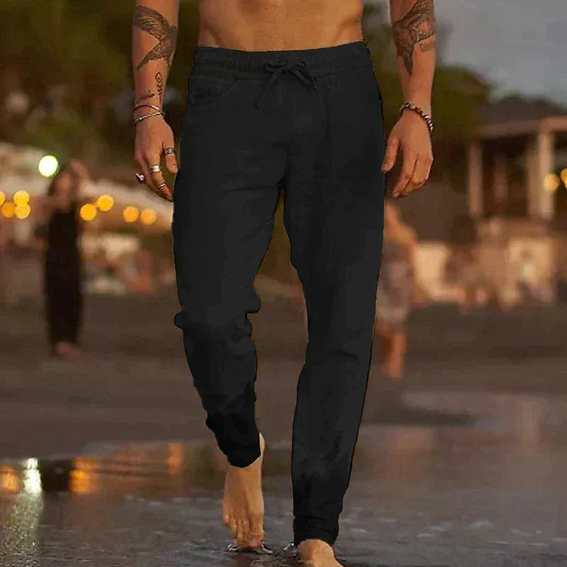 Schwarze Jogginghose für Herren, lässig am Strand getragen, ideal für Freizeit und Sport. Bequeme Passform, modisch und vielseitig einsetzbar.