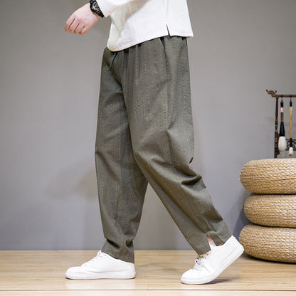 Person trägt weite, olivgrüne Hose mit Nadelstreifen und weiße Sneaker. Moderner, lässiger Stil, ideal für Freizeitmode und Streetwear.