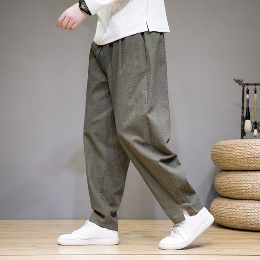 Person trägt weite, olivgrüne Hose mit Nadelstreifen und weiße Sneaker. Moderner, lässiger Stil, ideal für Freizeitmode und Streetwear.