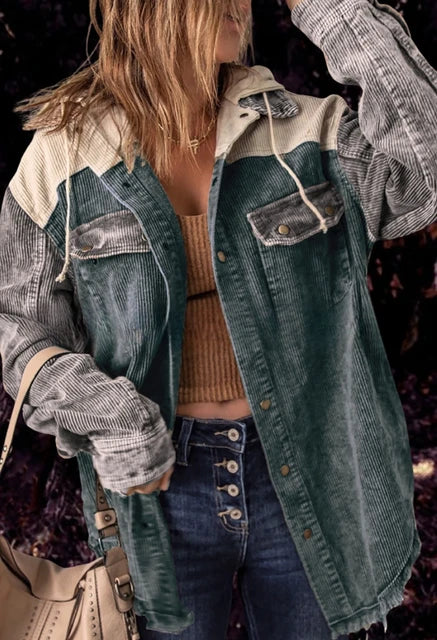 Frau in modischer Cordjacke mit Kapuze, gestreiftem Design und Knopfleiste, trägt beige Tasche. Trendige Herbstmode, lässiger Streetstyle.