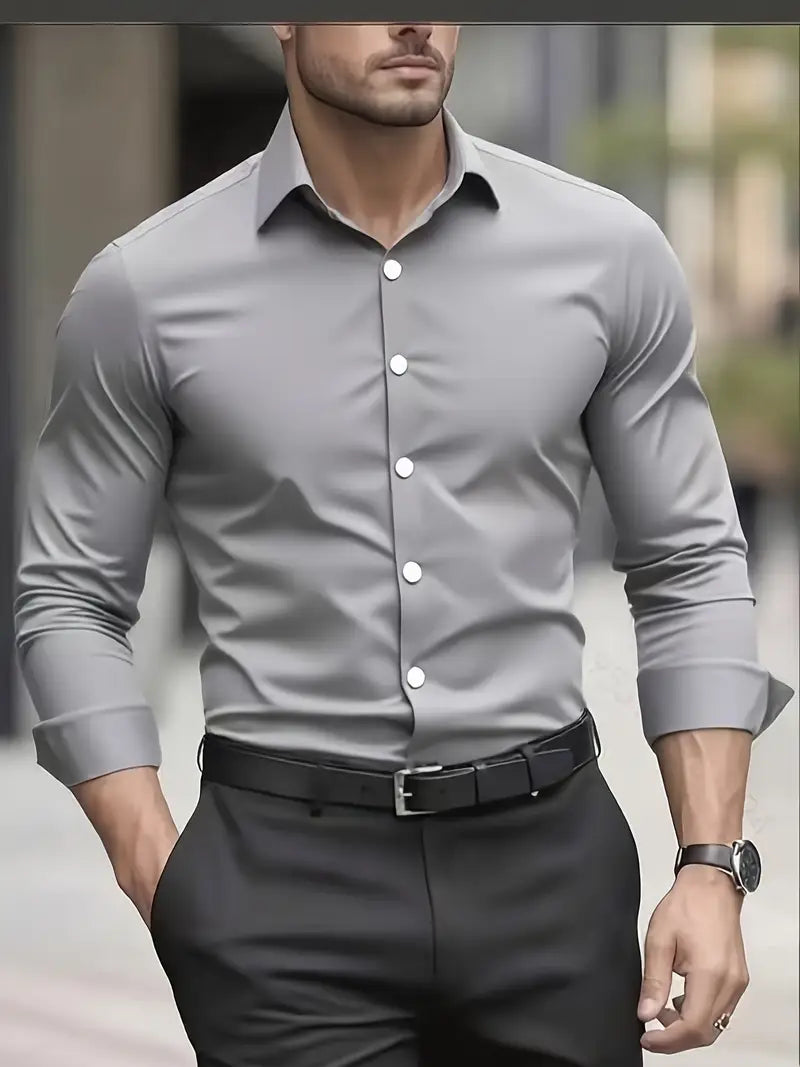 Mann in grauem Hemd und schwarzer Hose, eleganter Business-Look, moderne Herrenmode, stilvolles Outfit, Uhr am Handgelenk, urbaner Hintergrund.