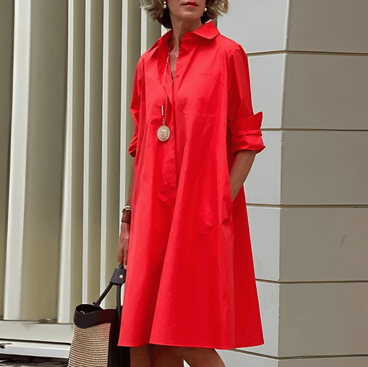 Frau in rotem Hemdkleid mit langen Ärmeln, trägt eine goldene Halskette und hält eine schwarze Tasche. Mode, Damenbekleidung, eleganter Stil.